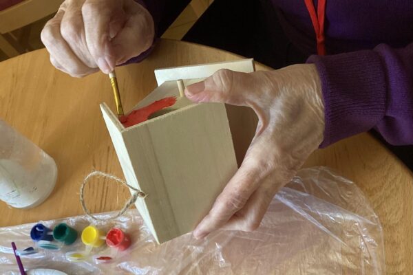 A resident painting a bird house. A resident painting a bird house.